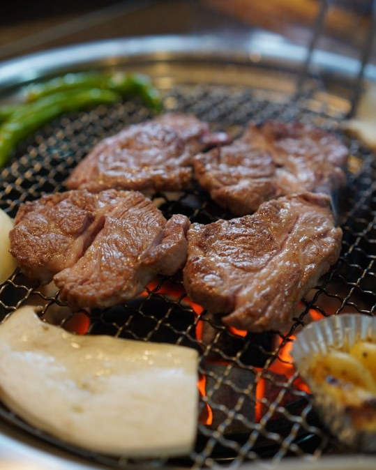 숯불 석쇠 위 구운 양고기 덩이, 새송이버섯·풋고추, 오른쪽에 은박 그릇(마늘로 보임)